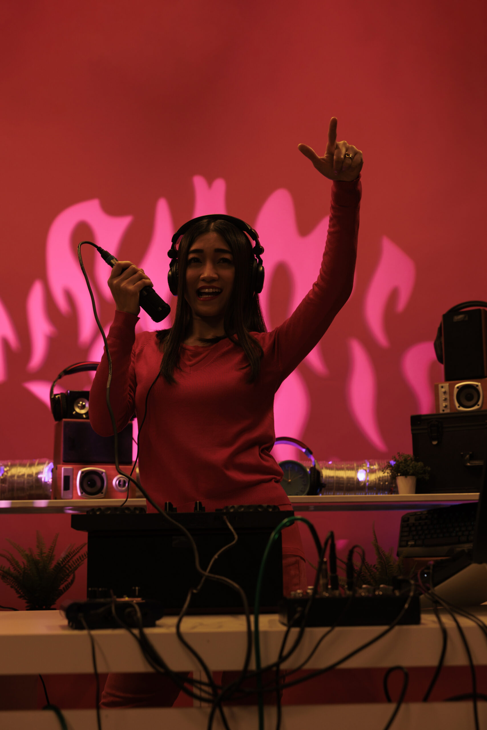 Cheerful asian artist doing performance at nightclub with professional audio equipment, enjoying partying and mixing electronic music. Performer playing sounds to produce melody at turntables