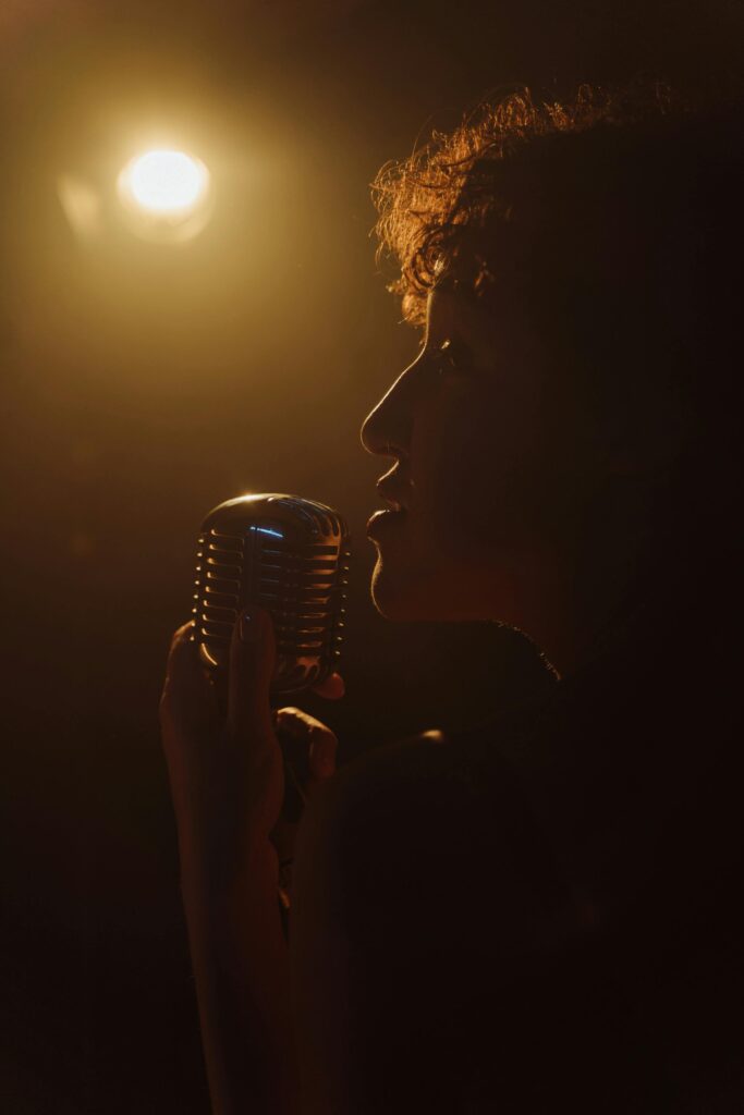 A singer passionately performs under a warm light, holding a vintage microphone.