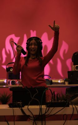 Cheerful asian artist doing performance at nightclub with professional audio equipment, enjoying partying and mixing electronic music. Performer playing sounds to produce melody at turntables