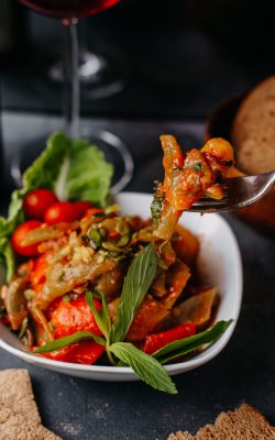 fried-meat-along-with-fried-vegetables-colorful-sliced-inside-white-plate-along-with-red-wine-bread-loafs-grey