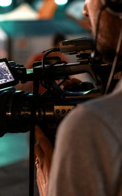 Professional cameraman recording poeple watching football in a public place at night