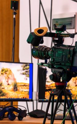 Professional video camera on a stand with monitors on a table in a studio. Virtual production